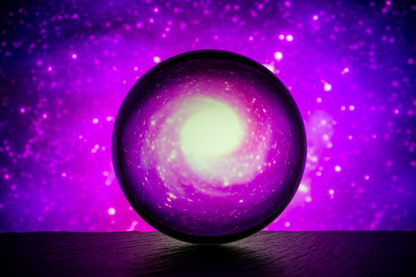 Crystal glass ball is lying on a stone surface on the colorful abstract background.